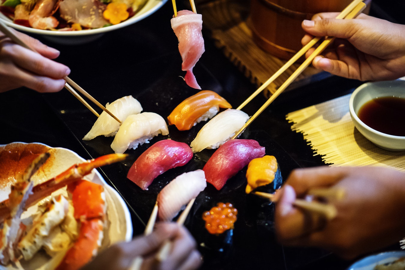 Groupe d'amis qui partage un repas typiquement japonais avec des sushis et des sashimis